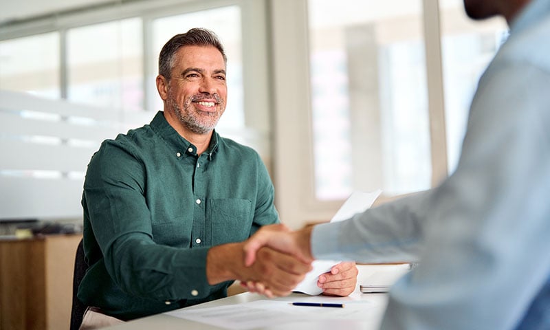 Middle-aged businessman shaking hands with a candidate he's interviewing for a job